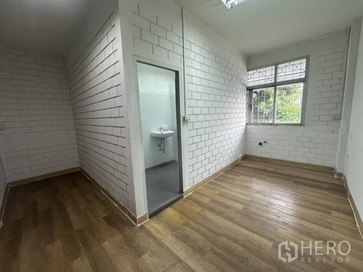 Warehouse for rent in Phra Khanong, Bangkok - Small office area with en-suite bathroom, white brick walls and wood floors.