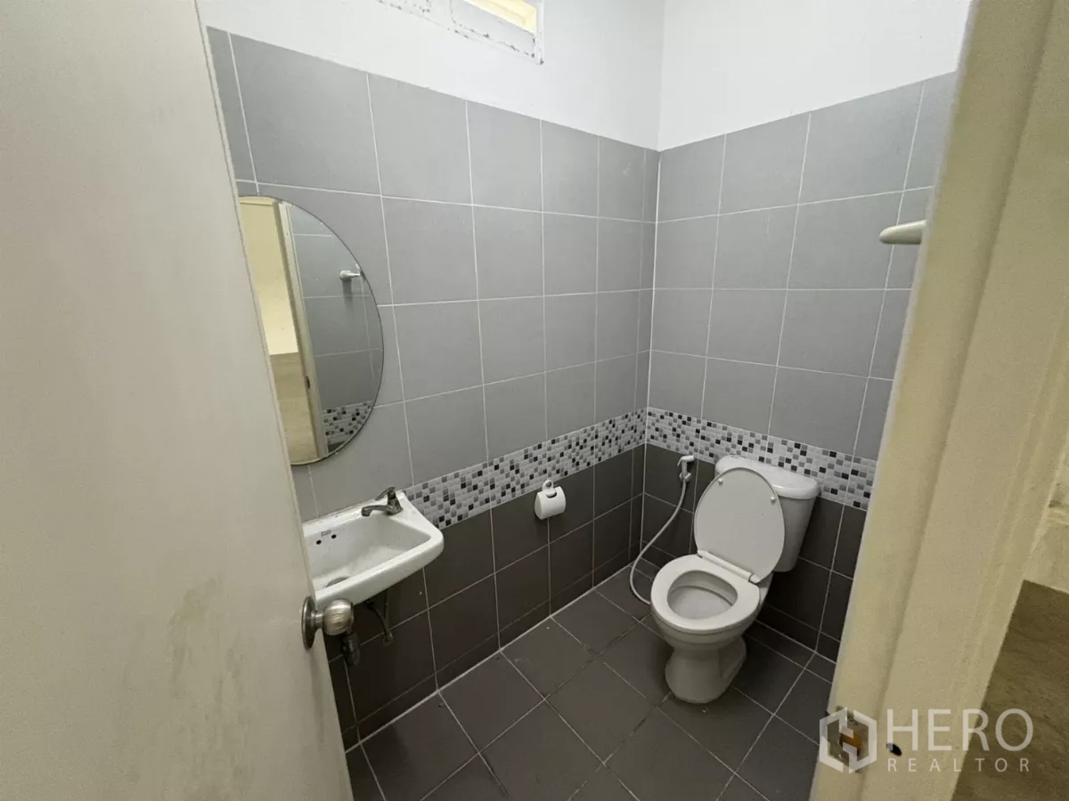 Factory for rent in Phra Samut Chedi, Samut Prakan - Clean tiled restroom with toilet, sink and bidet spray.