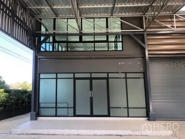 Factory for rent or sale in Bang Bo, Samut Prakan - Ground-floor glass office entrance beneath a metal canopy and mezzanine windows.