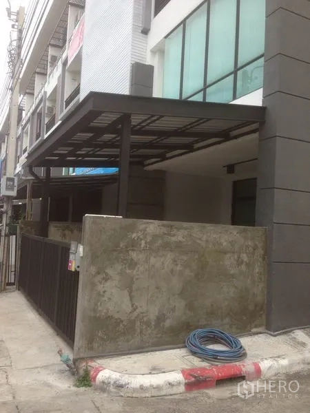Home Office for rent in Bang Phli, Samut Prakan - Side exterior of a townhouse-style commercial building with canopy roof and boundary wall.