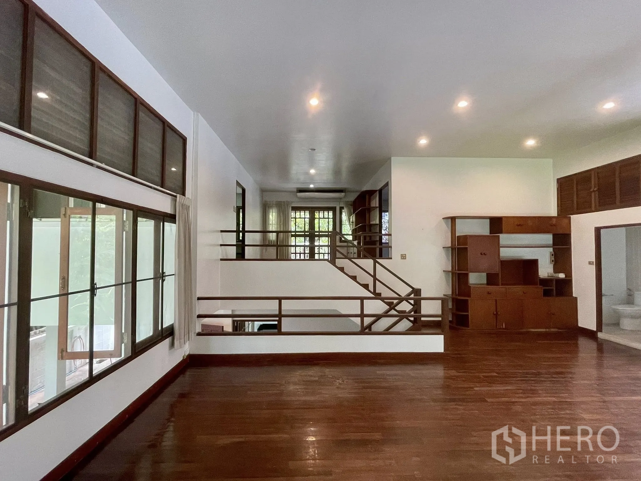 Detached House for rent in Pathum Wan, Bangkok - Split-level living area with hardwood floors, recessed lights, and a staircase.