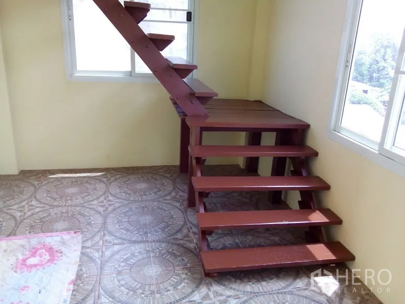 Shophouse for rent in Phra Khanong, Bangkok - Bright room with patterned floor tiles and compact wooden stairs by windows.