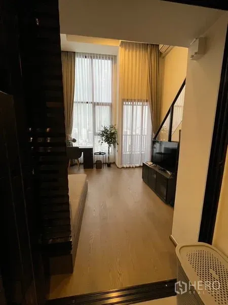 公寓 出租在Bang Rak, Bangkok - 从入口望向明亮客厅，超高窗帘与玻璃阳台门。