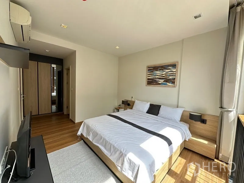 Condominium for rent in Watthana, Bangkok - Sunlit master bedroom with king bed, wood floors, and built-in wardrobe.