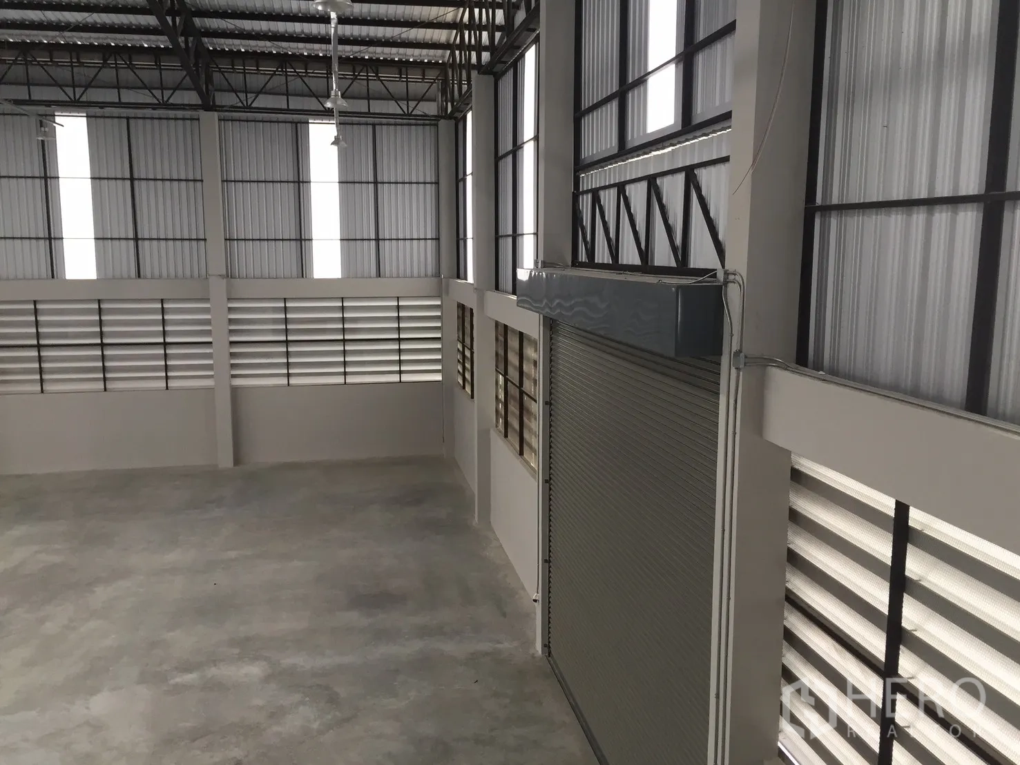 Warehouse for rent in Bang Phli, Samut Prakan - View from the mezzanine overlooking the roller shutter and louvered walls.