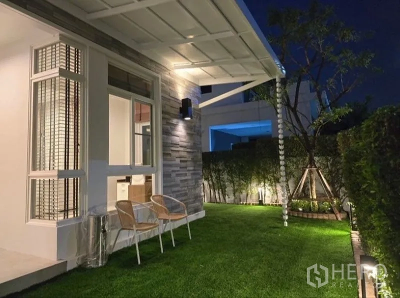 Detached House for rent - Night view of garden with canopy, wall lights and seating on manicured lawn.