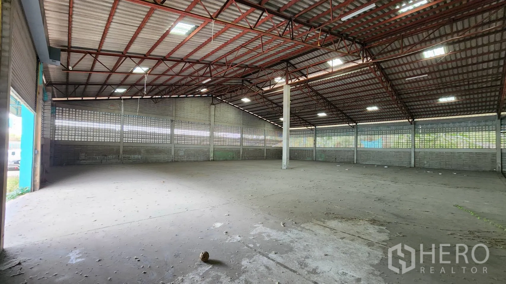 Warehouse for rent in Krathum Baen, Samut Sakhon - Spacious empty warehouse interior featuring a high steel truss roof, skylights, and a concrete floor.