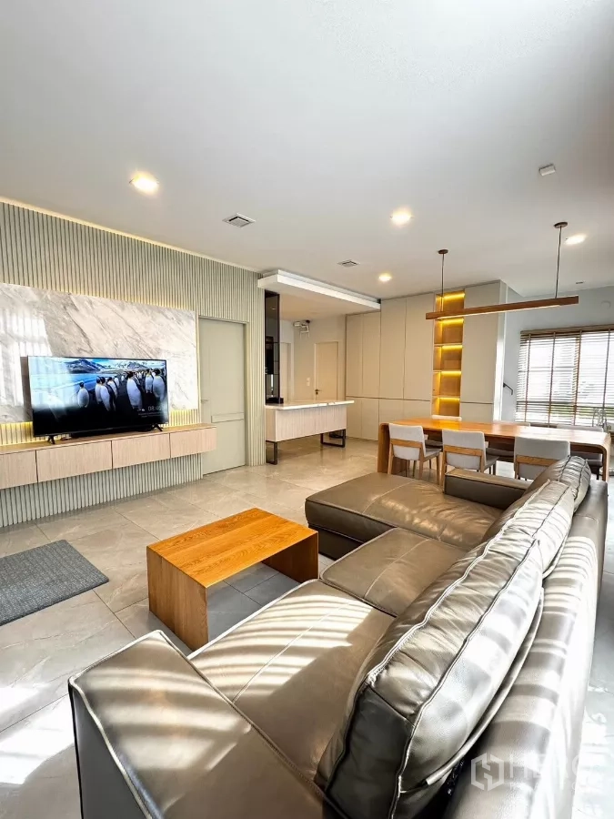 Detached House for rent in Prawet, Bangkok - Bright open-plan living room with large sectional sofa, TV feature wall and marble accents.