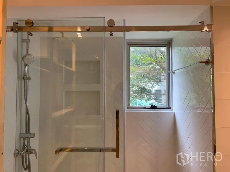 Condominium for sale in Watthana, Bangkok - Glass-enclosed shower with rain head and a window for natural light.