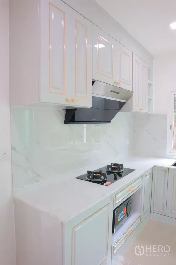 独立式住宅 出租在Bang Phli, Samut Prakan - 内置橱柜特写，灶台、油烟机与大理石背景。