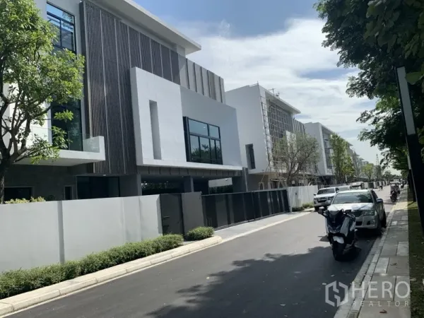 独立式住宅 出租在Saphan Sung, Bangkok - 封闭社区内安静林荫街道，两侧现代三层住宅与路边停车