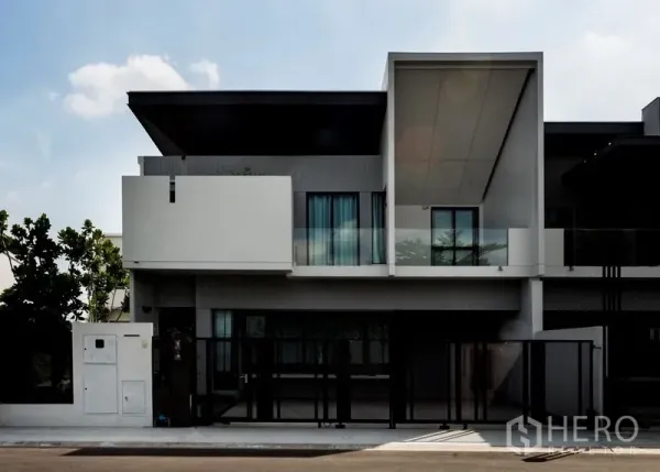 Townhouse for rent in Samut Prakan - Modern two-storey townhouse facade with large balcony, tinted glass and gated parking in Bang Phli.