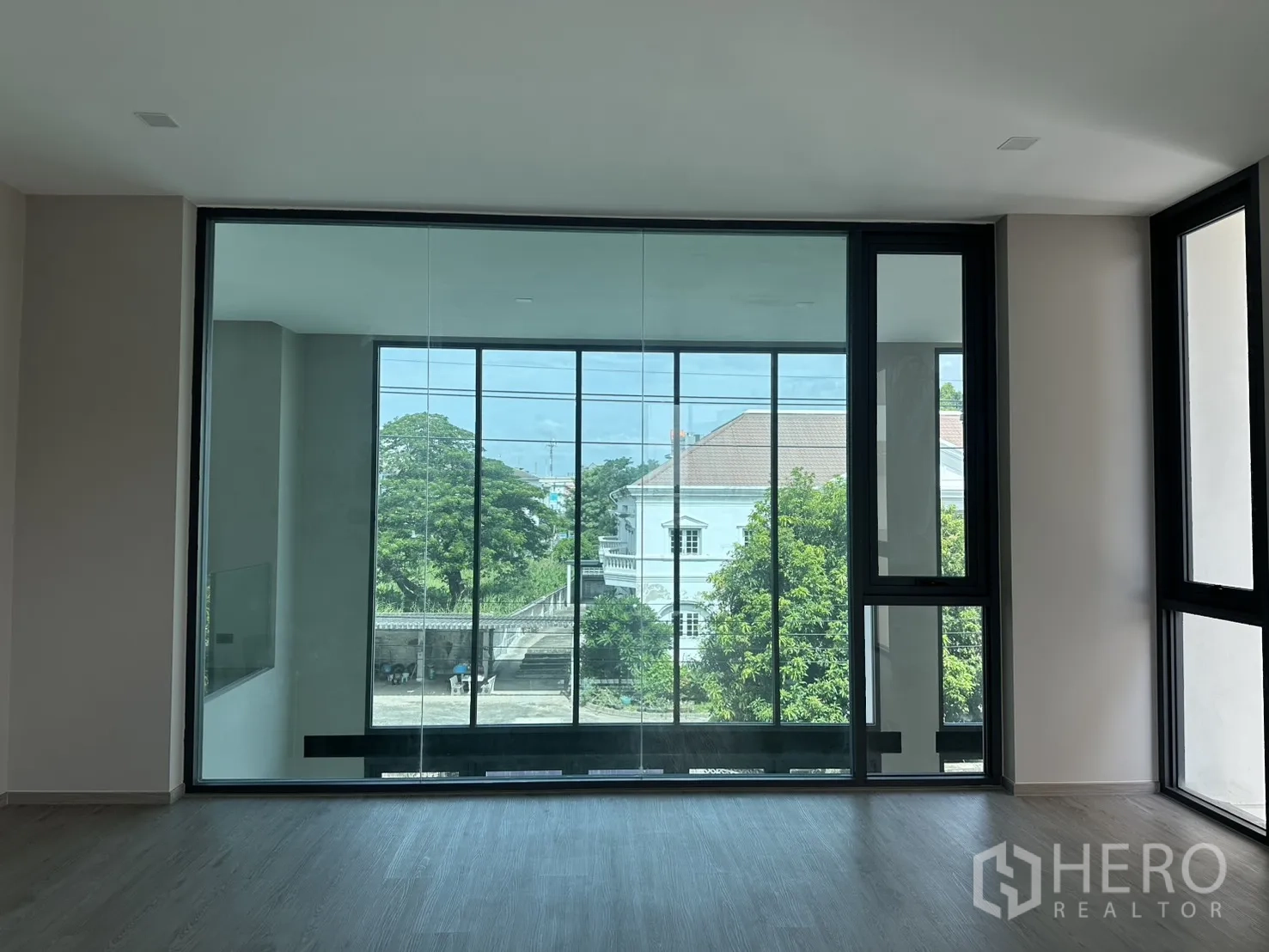 家庭办公室 for rent or sale in Suan Luang, Bangkok - 室内玻璃墙望向另一间带窗房间与绿意。