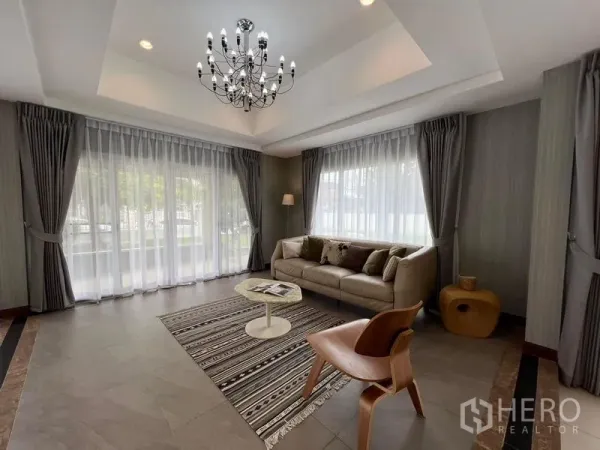 Detached House for sale in Mueang Pathum Thani, Pathum Thani - Bright living room with chandelier, large corner windows and sofa in Mueang Pathum Thani detached house