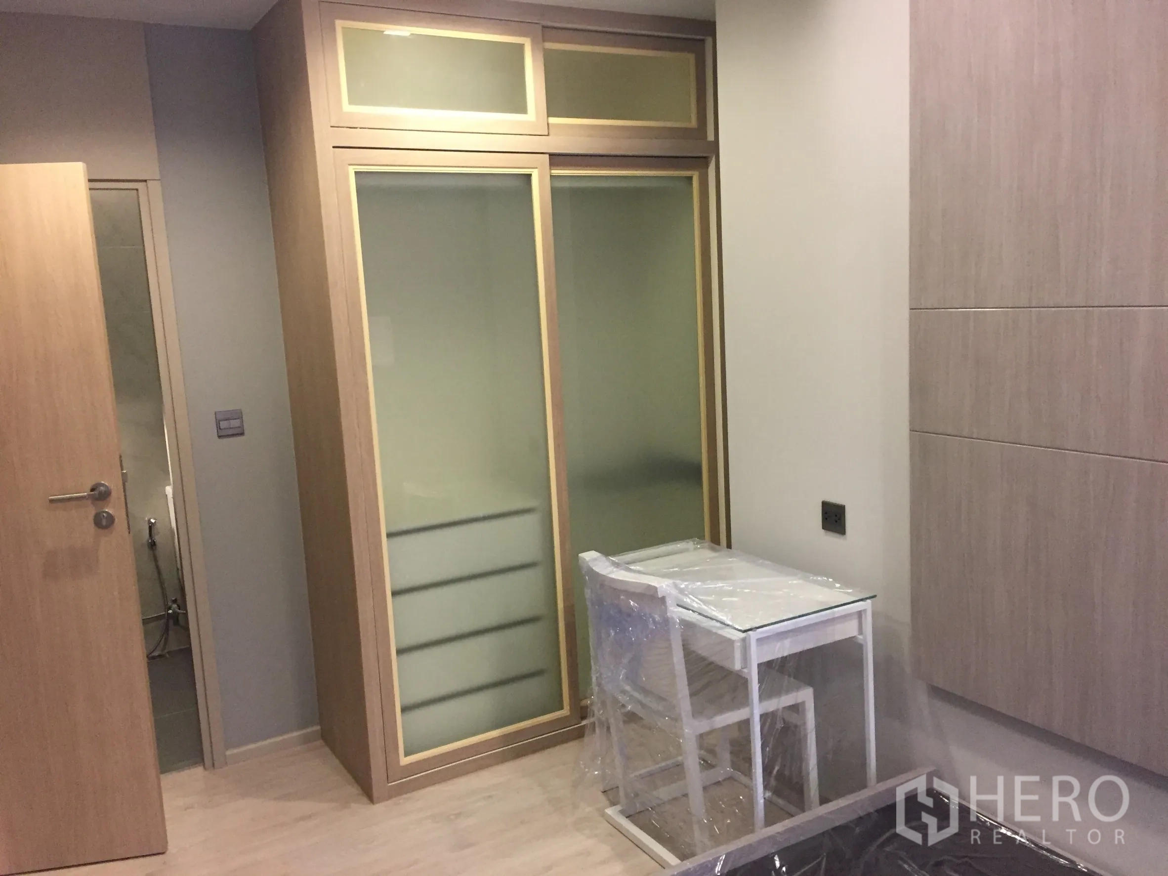 Condominium for rent in Watthana, Bangkok - Bedroom with built-in sliding wardrobe and compact work desk in light wood tones.