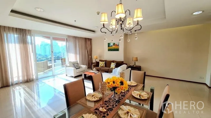 คอนโด ให้เช่าในWatthana, Bangkok - โต๊ะรับประทานอาหารใต้โคมระย้า มุมมองสู่ห้องนั่งเล่นสว่าง ประตูบานเลื่อนออกระเบียงเห็นวิวเมือง