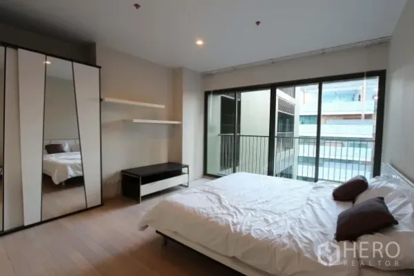 公寓 出租在Watthana, Bangkok - 明亮卧室，木地板，镜面衣柜，落地推拉门连接小阳台。