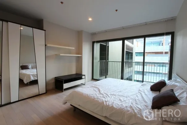 公寓 出租在Watthana, Bangkok - 明亮卧室，木地板，镜面衣柜，落地推拉门连接小阳台。