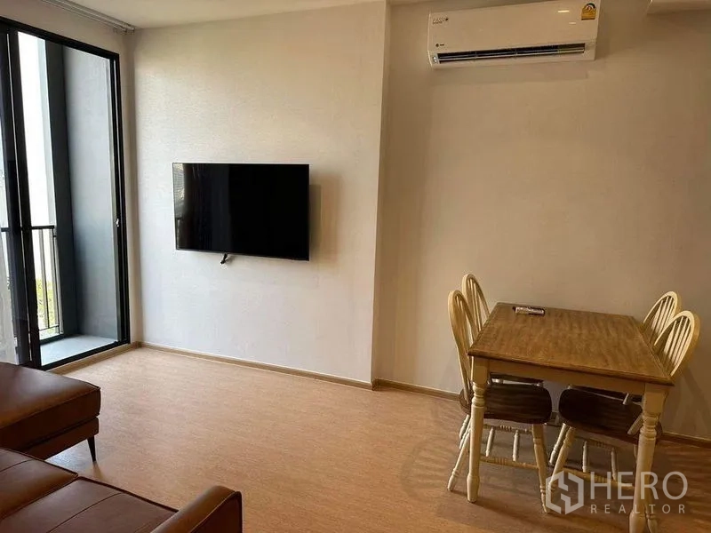 公寓 出租在Watthana, Bangkok - 客厅设壁挂电视与餐桌，推拉门通阳台并配壁挂空调。
