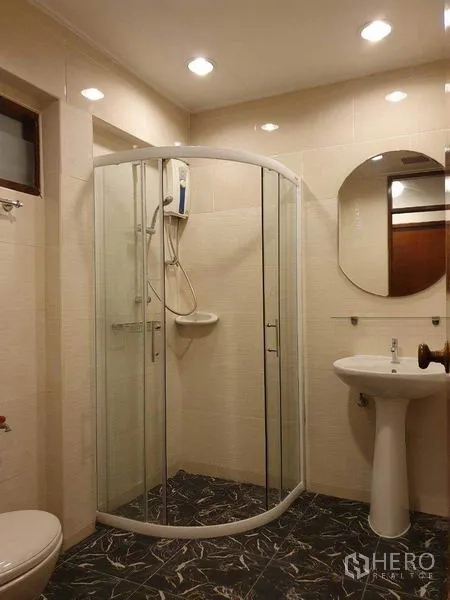 Detached House for rent in Phra Khanong, Bangkok - Modern bathroom with curved glass shower enclosure and pedestal sink.