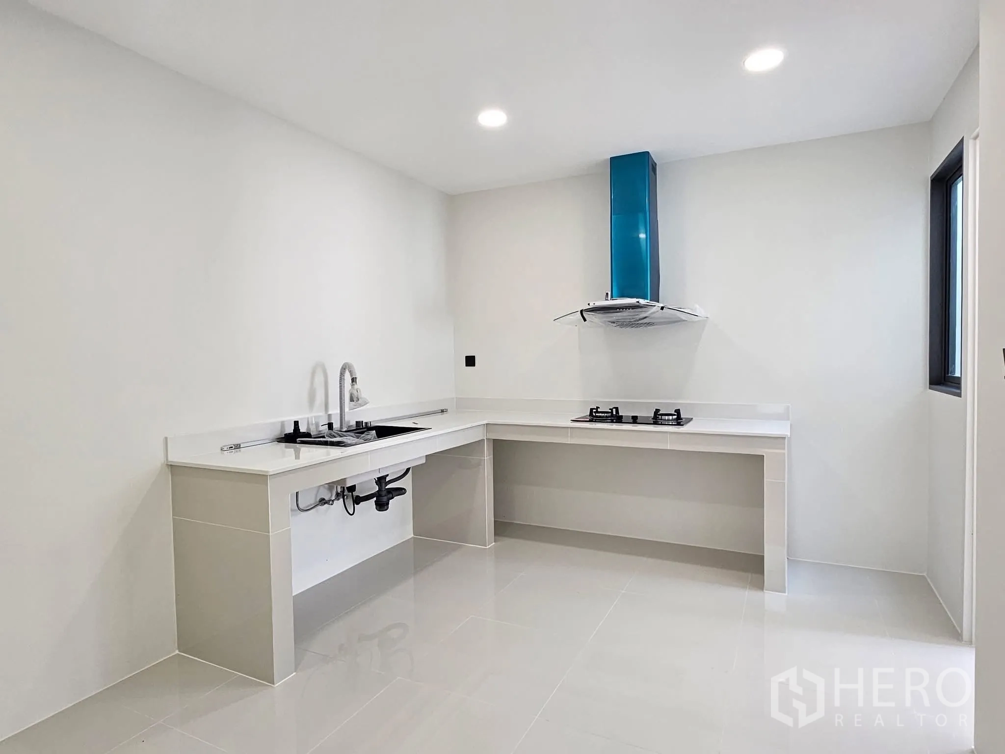 独栋房屋 for sale in Lat Phrao, Bangkok - 极简白色厨房，L型台面，双燃气灶与抽油烟机。