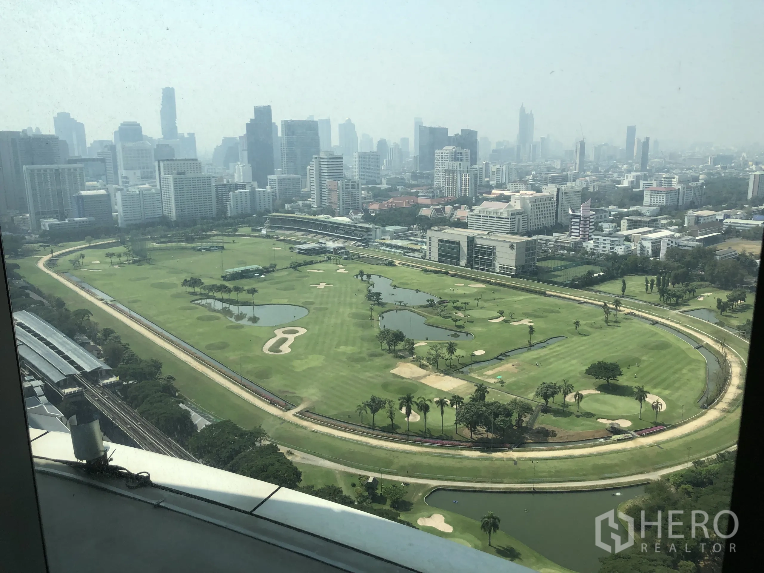 公寓 出租在Pathum Wan, Bangkok - 高层窗口俯瞰巴吞旺区的高尔夫球场与城市天际线。
