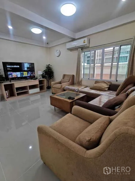 Townhouse for rent in Chatuchak, Bangkok - Living room with L-shaped sofa, TV console and air conditioning.