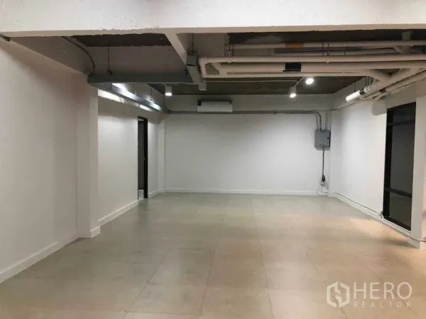 Office Space for rent in Phaya Thai, Bangkok - Open-plan 65 sqm office with exposed ceiling pipes, white walls and tiled flooring.