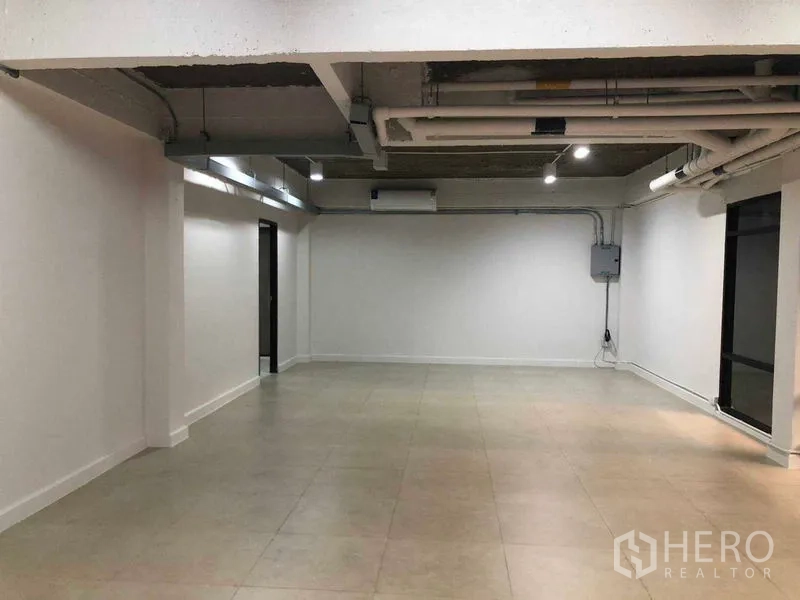 Office Space for rent in Phaya Thai, Bangkok - Open-plan 65 sqm office with exposed ceiling pipes, white walls and tiled flooring.