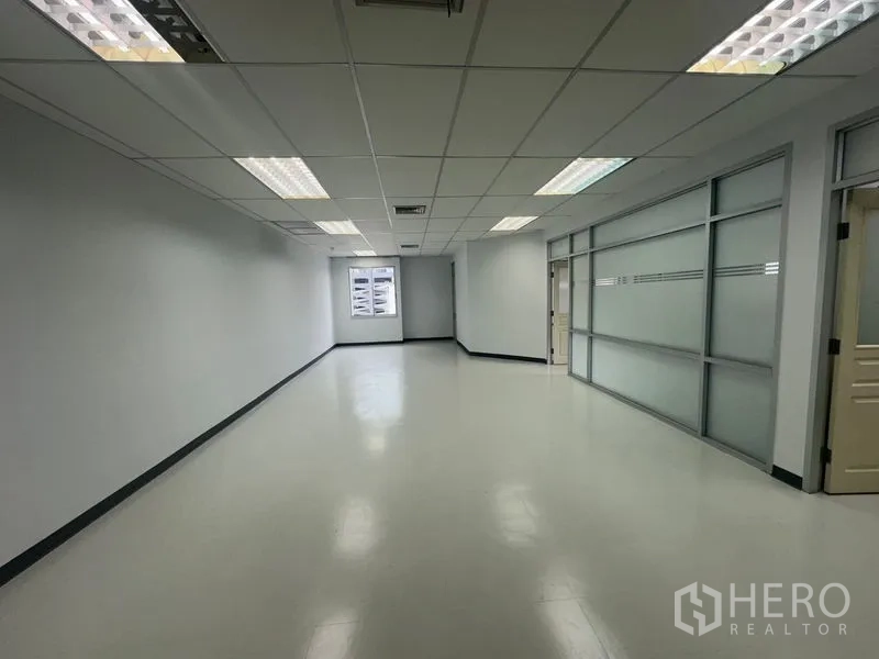 Office Space for rent in Bang Rak, Bangkok - Long workspace with a window at the end and a frosted glass wall along the right side.