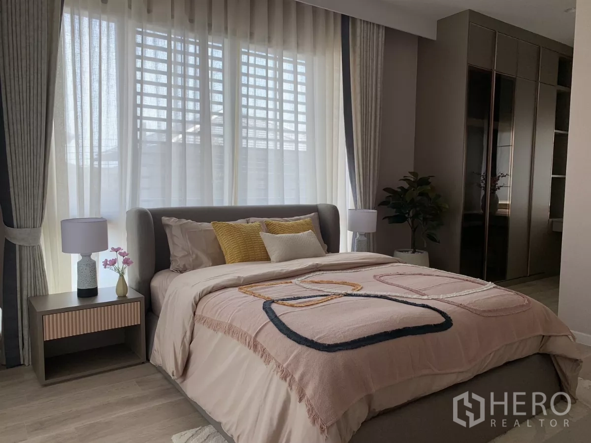 Detached House for rent in Bang Kapi, Bangkok - Cozy bedroom with soft pink bedding, large windows and fitted wardrobes.