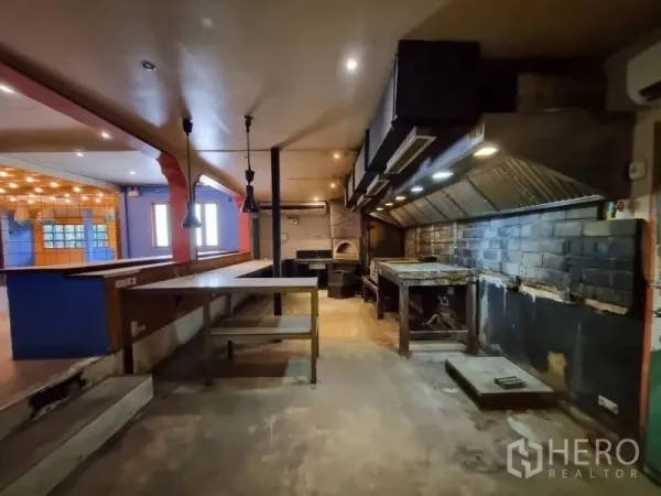 Detached House for rent in Khlong Toei, Bangkok - Large industrial-style kitchen with extraction hoods, prep counters and concrete floor.