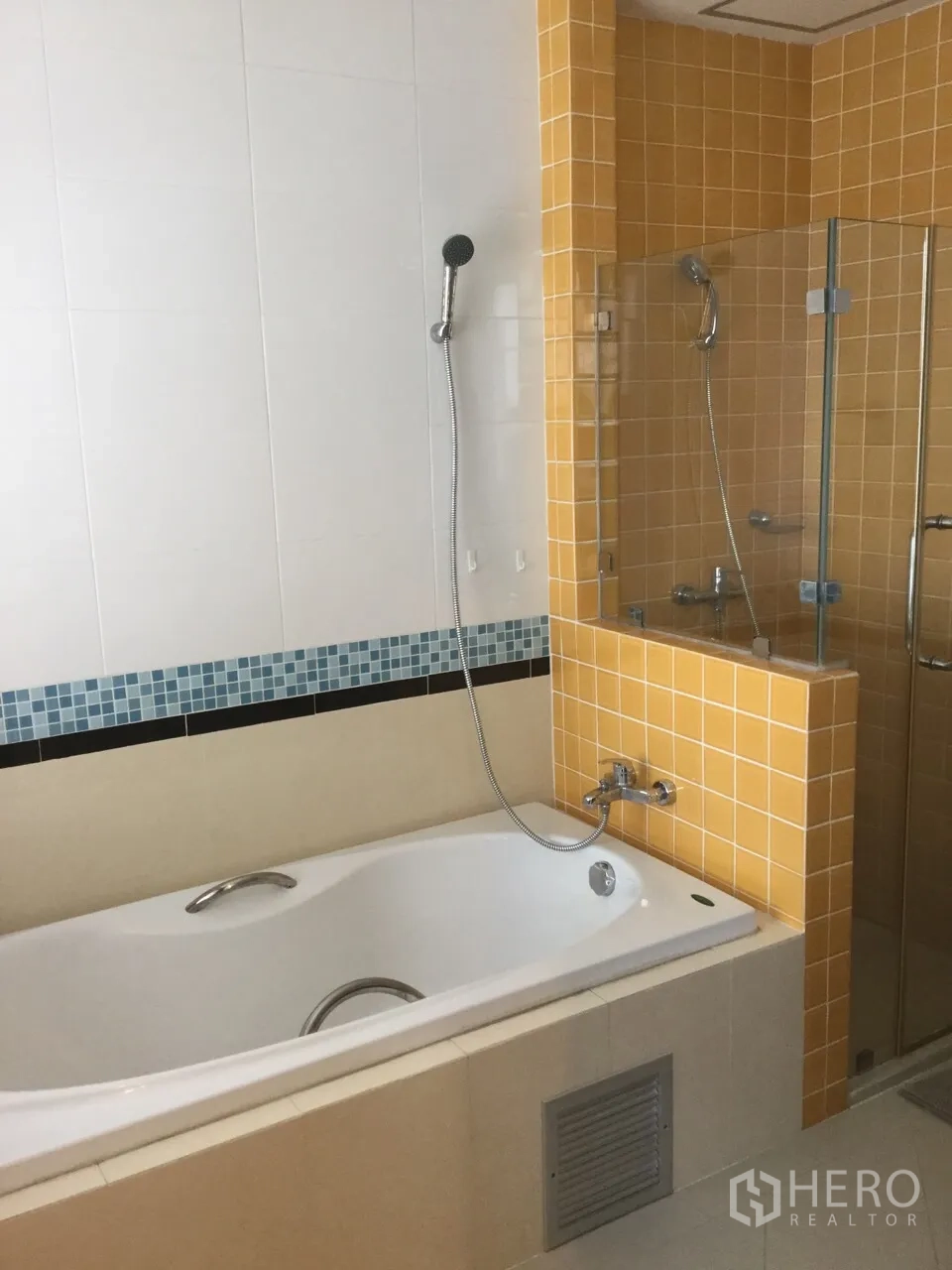 Condominium for rent in Khlong Toei, Bangkok - Bathroom with bathtub, handheld shower and separate glass-enclosed shower with yellow tile accents.