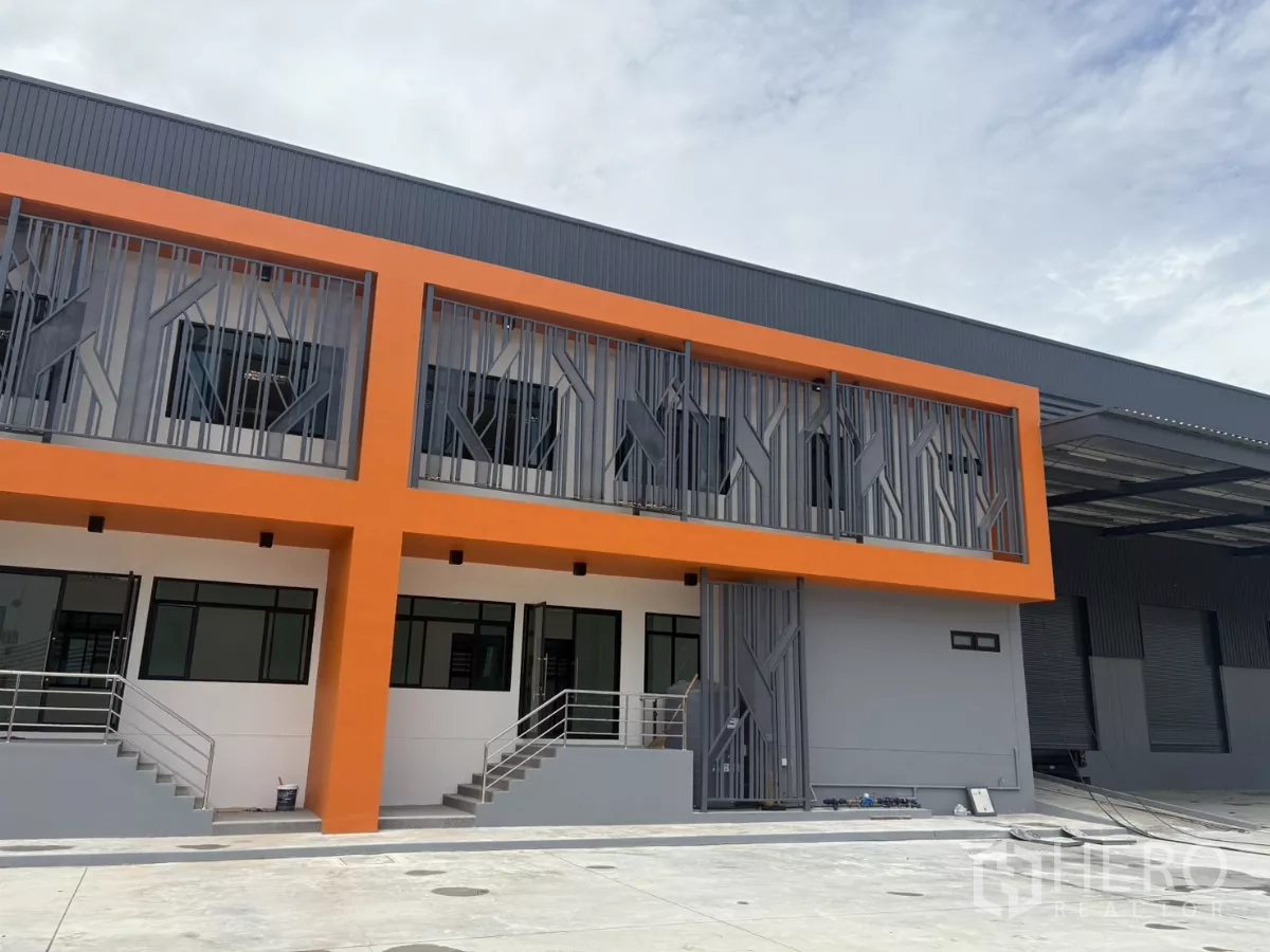 工厂 出租在Bang Pakong, Chachoengsao - 新建工厂外观，橙色立面与办公室窗户，前方为抬高入口（邦巴功）。