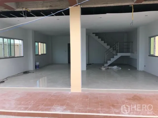 Factory for rent in Khlong Luang, Pathum Thani - Open-plan ground floor area with tiled finish and staircase leading to mezzanine office.