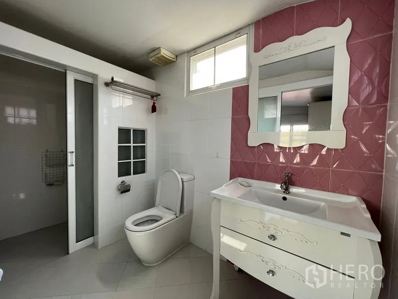 Detached House for rent in Bang Kapi, Bangkok - Bathroom with white vanity, pink accent wall, toilet and separate shower area.
