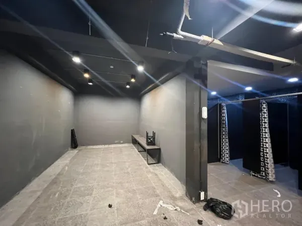 Showroom for rent in Mueang Samut Prakan, Samut Prakan - Dark interior room with spotlights, bench seating and curtained changing area