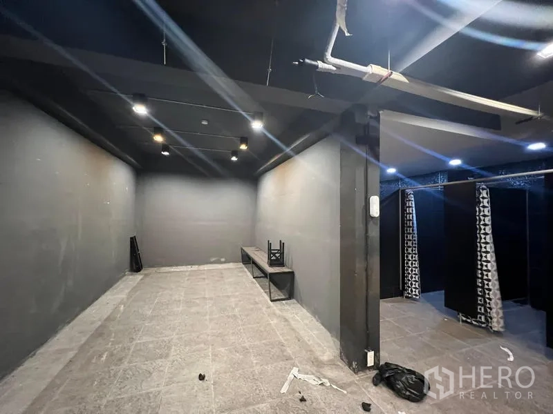Showroom for rent in Mueang Samut Prakan, Samut Prakan - Dark interior room with spotlights, bench seating and curtained changing area