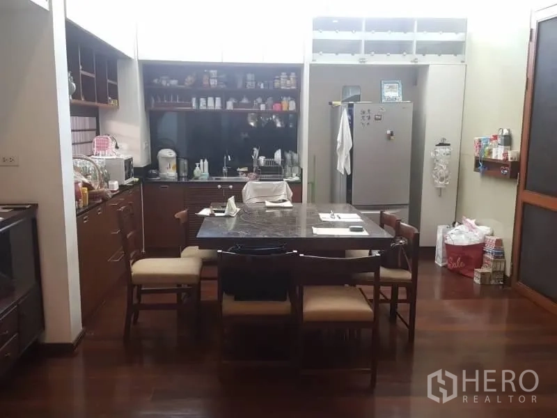 Home Office for rent or sale in Bang Rak, Bangkok - Family kitchen and dining area with wooden cabinets, center table and refrigerator.