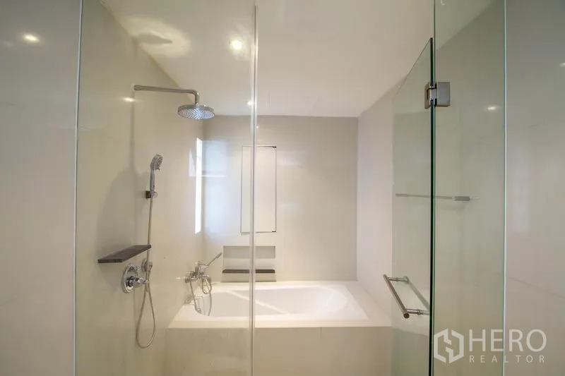 Condominium for rent in Watthana, Bangkok - Modern bathroom with glass shower, rain head and built-in bathtub.