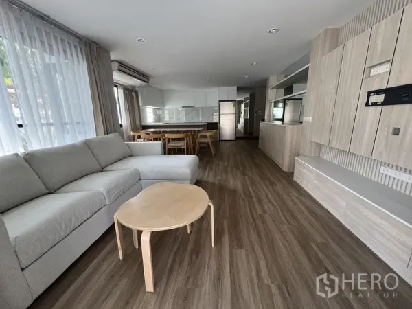 独立式住宅 出租在Bang Rak, Bangkok - 宽敞客厅，落地窗与电视背景墙，温暖木质地面。