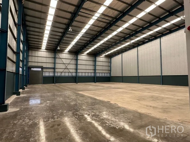 Factory for rent in Bang Phli, Samut Prakan - Empty storage bay with high ceiling, steel columns and smooth concrete surface.