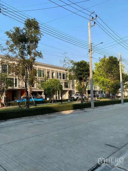 Townhouse for rent in Bang Kapi, Bangkok - Tree-lined internal road with contemporary townhomes and a small park strip.
