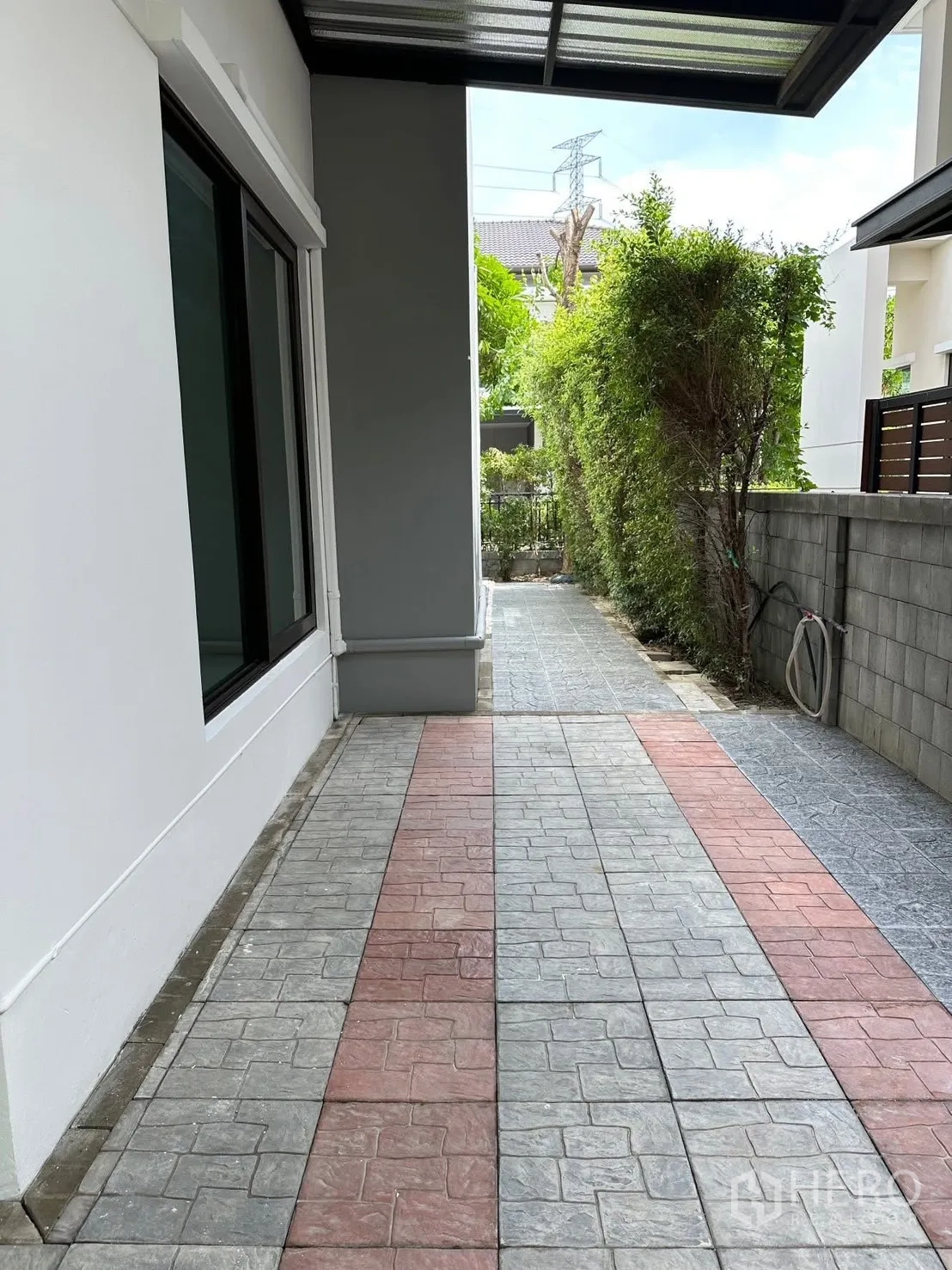 Detached House for rent in Bang Phli, Samut Prakan - Covered side walkway with patterned pavers and a green hedge beside the house.