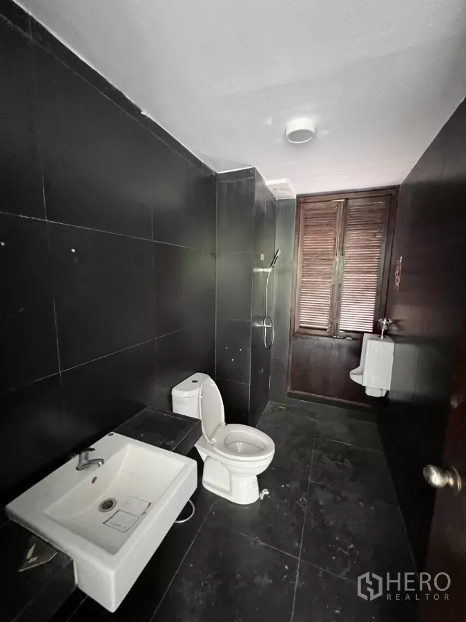 Retail Space for rent in Khlong Toei, Bangkok - Black-tiled restroom with sink, toilet and window.