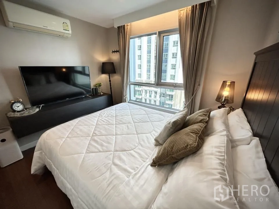 คอนโด for rent in Huai Khwang, Bangkok - ห้องนอนพร้อมหน้าต่างบานใหญ่ ทีวี และโคมไฟข้างเตียง