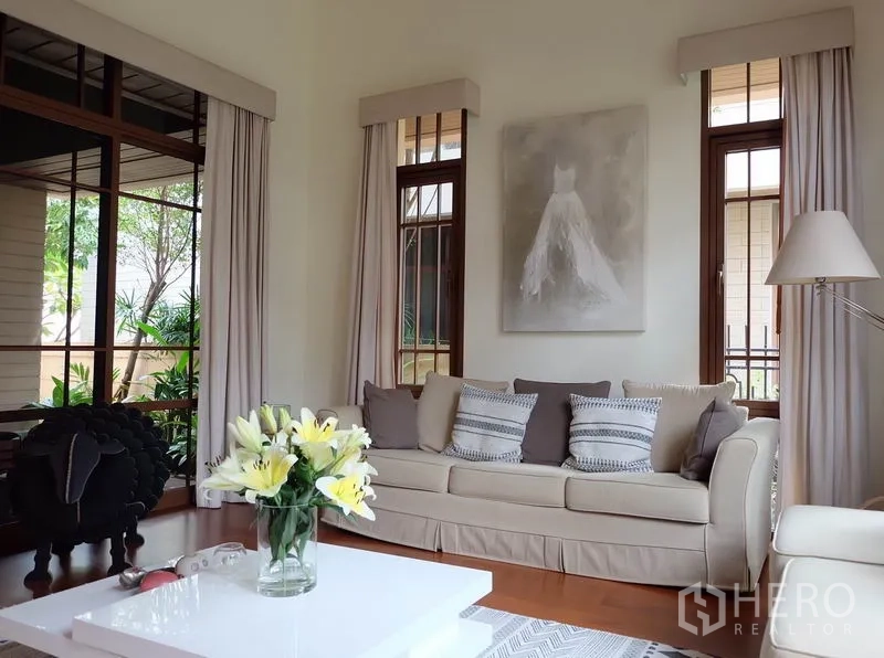บ้าน ให้เช่าในWatthana, Bangkok - มุมมองเพิ่มเติมของห้องนั่งเล่นสว่าง โซฟาสีเอิร์ธโทน โต๊ะกลางสีขาว และแจกันดอกไม้