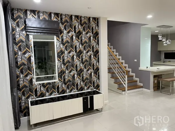 Detached House for rent in Bang Kapi, Bangkok - Open-plan living area with feature wall, staircase and a view toward the modern kitchen.