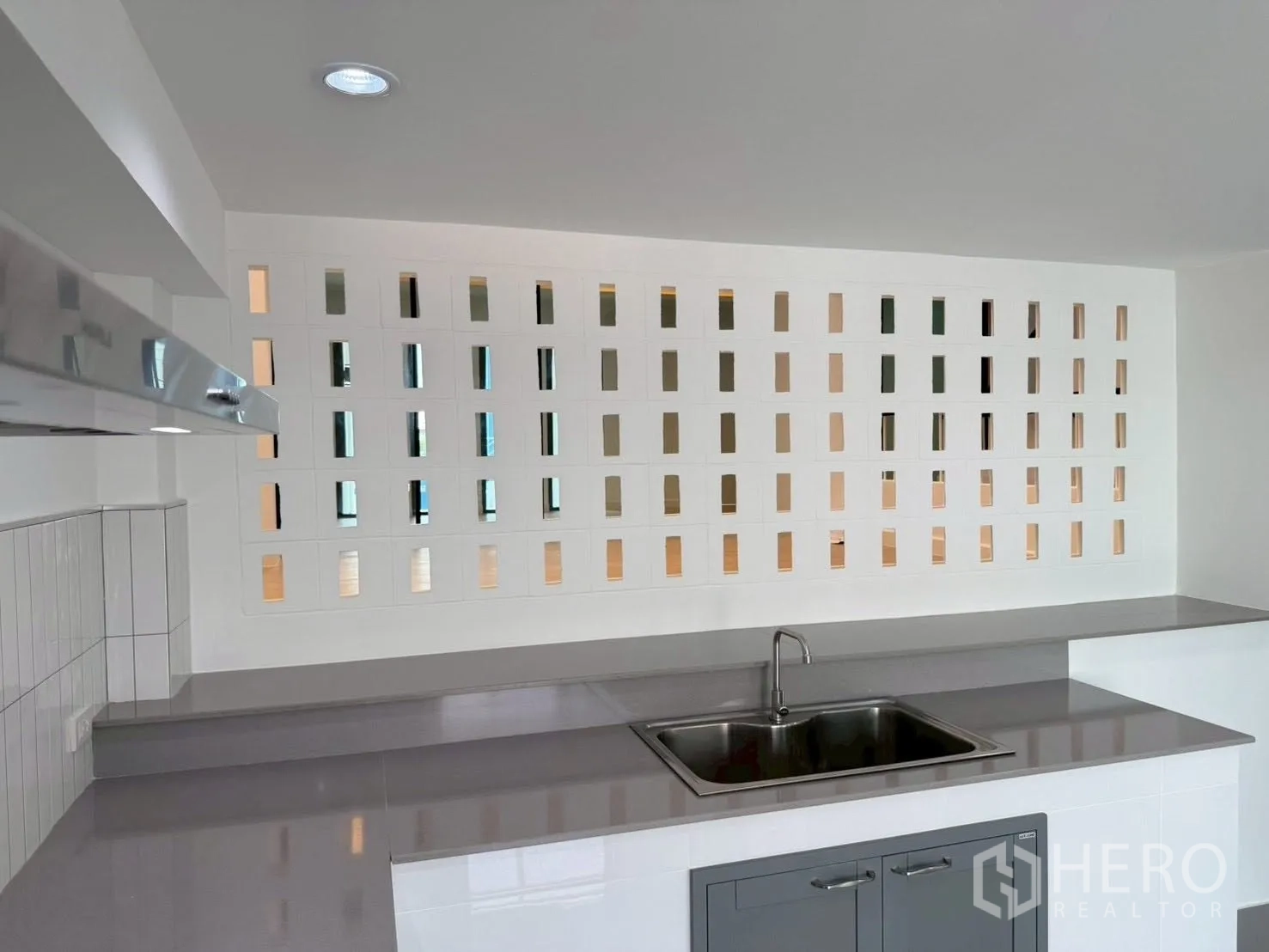 Townhouse for sale in Phra Khanong, Bangkok - Kitchen counter with stainless sink and decorative ventilation block wall.