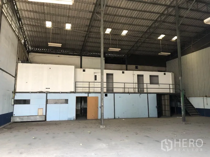 Warehouse for rent in Lam Luk Ka, Pathum Thani - Spacious warehouse interior with high steel roof, bright lighting and mezzanine offices overlooking the open floor.